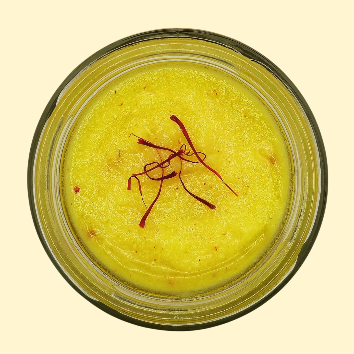 Kashmiri Mongra Saffron Ghee in a jar with saffron strands on top, showcasing its rich yellow color.